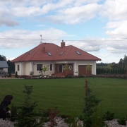 Dom czterospadowy w kącie ogrodu.